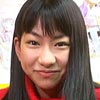 Juri Ihata with long black hair smiles dressed in a red sweater.