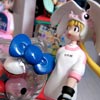 The Kumi and Kasumi figure stand either side of a miniature Hello Kitty gumball machine. Yuri is in the background.
