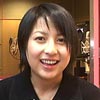Kaori Shimizu with short black hair smiles dressed in a black jacket.