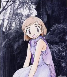 Kumi in blue casual clothing sits and smiles with a dark forest background.